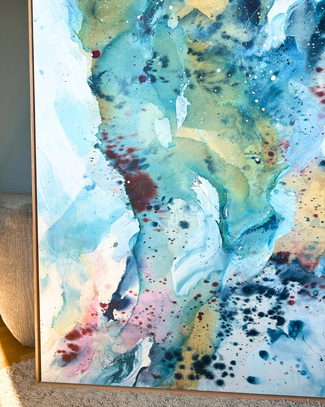 Close-up detail of large original abstract canvas painting in natural oak float frame – expressive fluid layers in teal, sky blue, gold, blush pink and white with dynamic brushwork and fine paint details.