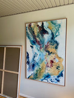 Abstract painting in warm gold and burgundy with cool teal and blue tones, 100x150 cm on canvas in oak frame – Soft #13 by Mette Lindberg, shown horizontally

