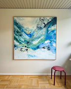 Large square original abstract painting in teal, cobalt blue and white, in natural oak float frame – expressive fluid brushwork and black paint splatter on canvas, shown on white wall with parquet floor in Scandinavian interior