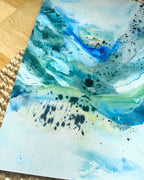 Close-up of abstract art print with flowing blue, teal and green paint, organic fluid shapes and black ink splatter