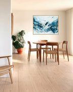 Large abstract blue painting in oak frame above round dining table by Mette Lindberg