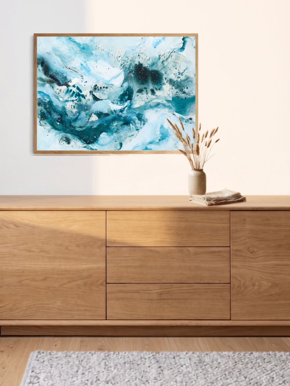 Abstract art print Soft #14 by Mette Lindberg – teal, white and dark blue fluid composition. The art poster is in aok frame above oak cabinet. 