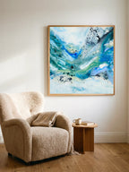 Square format art print in abstract style. The art poster is framed in oak ang hung above a soft armchair.
