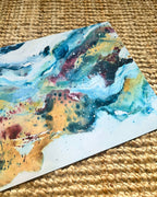 Close-up of colourful abstract art print – flowing blue, golden yellow and deep red paint with organic textures and ink drops