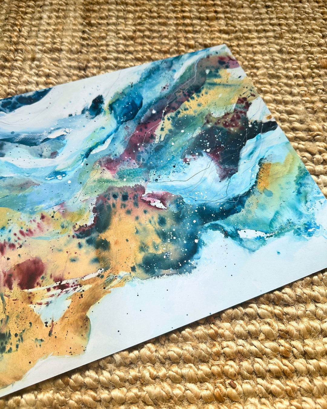 Close-up of colourful abstract art print – flowing blue, golden yellow and deep red paint with organic textures and ink drops