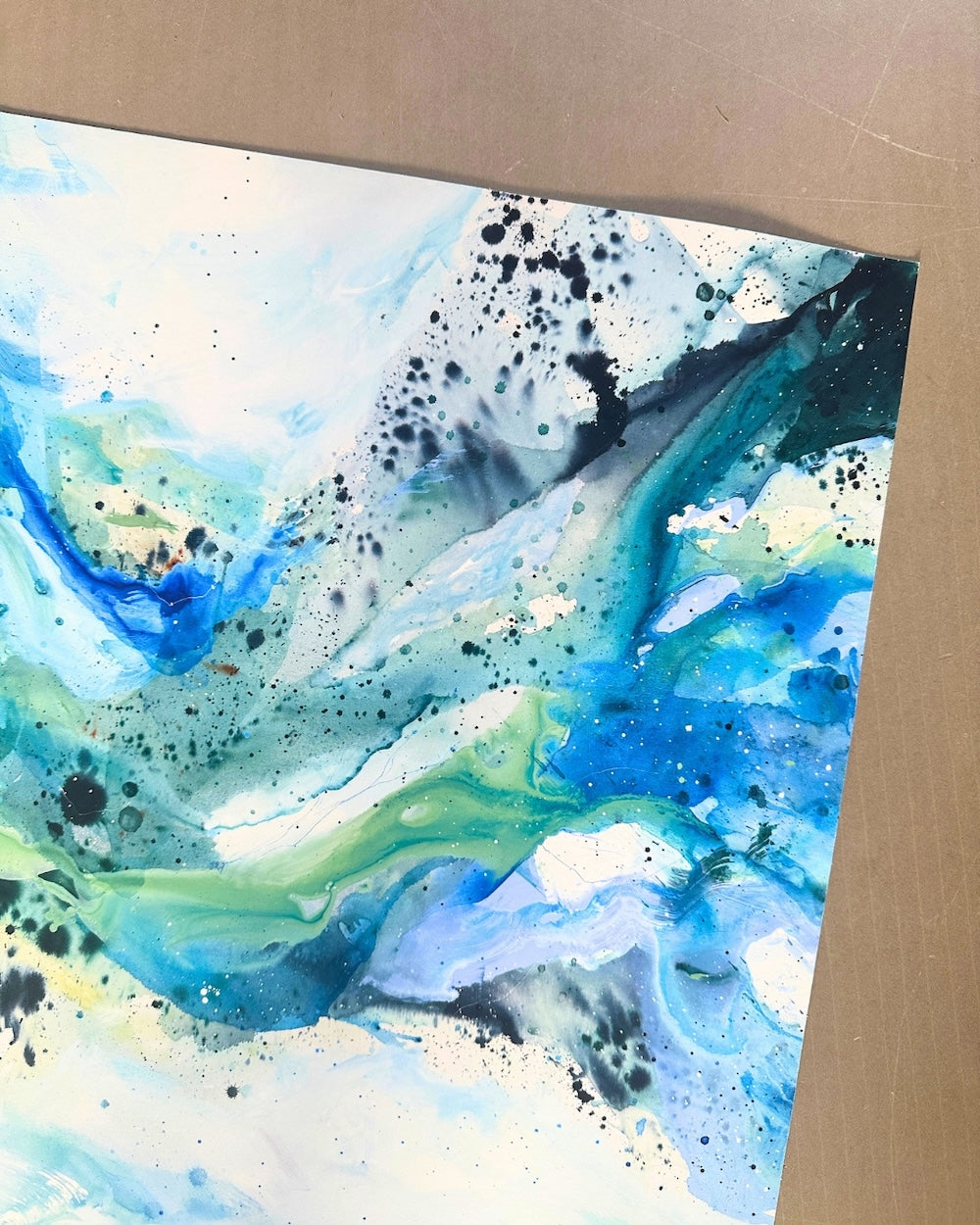 Detail shot of abstract painting by Mette Lindberg – sweeping blue and green fluid paint with black ink droplets on white canvas