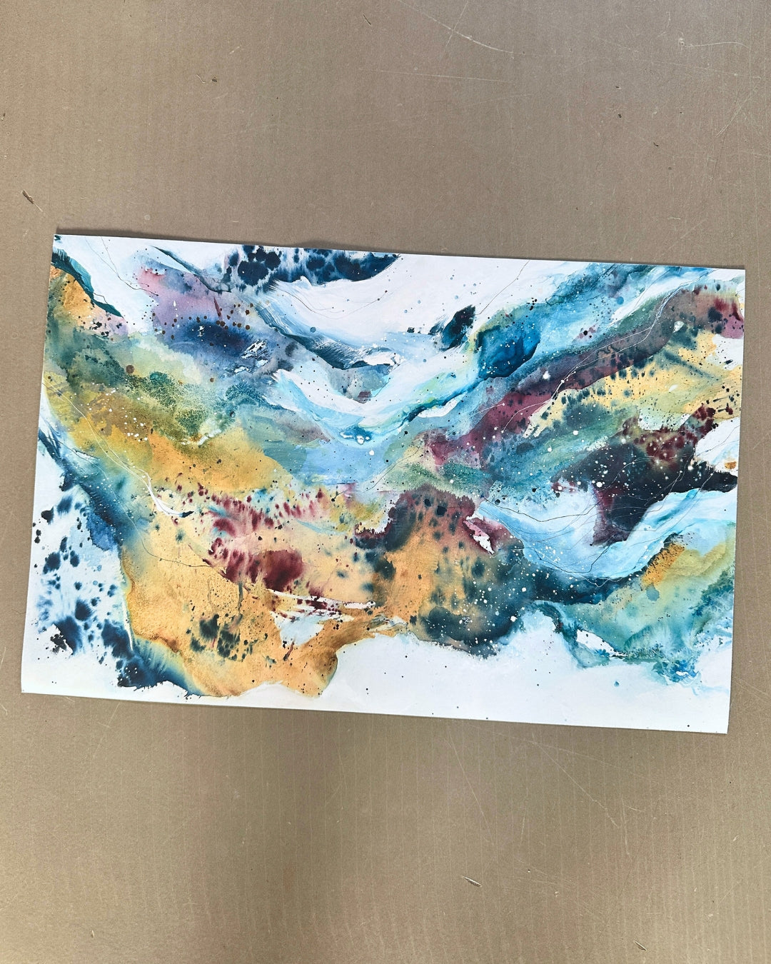 Horizontal abstract art print by Mette Lindberg – sweeping blue, ochre and burgundy fluid paint on white paper, landscape format