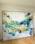 Large abstract painting on canvas in teal, blue and gold tones with oak frame, standing against a white wall on herringbone oak parquet floor
